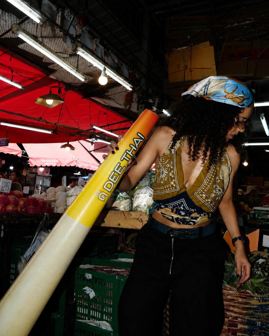 Campaign talent holding a large Dee Thai branded prop at the fruit market